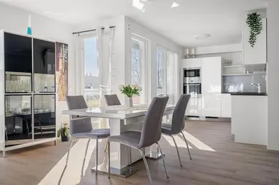 a white kitchen with a dining table and chairs at A cozy three bedroom apartment for rent in Heimdal