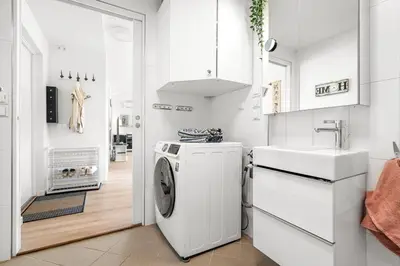 a white kitchen with a washing machine and a sink at A cozy three bedroom apartment for rent in Heimdal