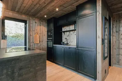 a kitchen with black cabinets and a large window at Modern Mountain Cabin Near Syningtoppen in Torpo