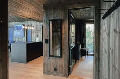 a room with a wooden wall with a mirror at Modern Mountain Cabin Near Syningtoppen in Torpo