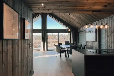 a dining room with a table and chairs and a large window at Modern Mountain Cabin Near Syningtoppen in Torpo