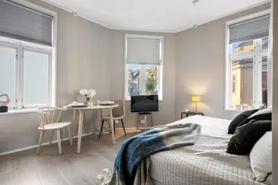 a bedroom with a bed and a table and windows at Roomsly - Cozy Hilltop Hideout in Central Bergen in Bergen