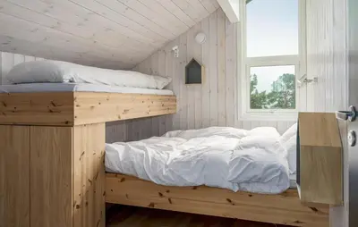a bedroom with a bunk bed with white sheets and a window at 2 Bedroom Cozy Home In Edland in Vågsli
