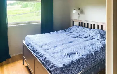 a bed with a blue comforter in a room with a window at Nice Apartment In Tisleidalen With Wifi in Tisleidalen