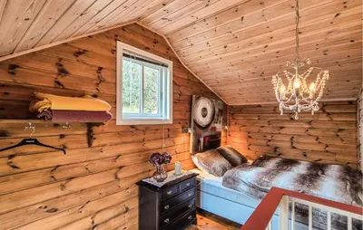 a bedroom in a log cabin with a bed and a chandelier at Nice Home In Valen With House Sea View in Valen