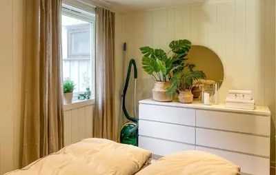 a bedroom with a dresser with plants and a window at 1 Bedroom Gorgeous Apartment In Kvisvik in Kvisvik