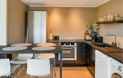 a kitchen with a table and some white chairs at 1 Bedroom Gorgeous Apartment In Kvisvik in Kvisvik