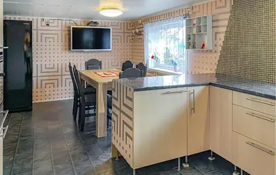 a kitchen with a table and a tv on the wall at Pet Friendly Apartment In Harøy in Steinshamn