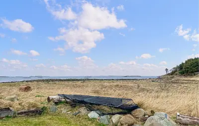 a tarp sitting on top of a field next to the ocean at Pet Friendly Apartment In Harøy in Steinshamn