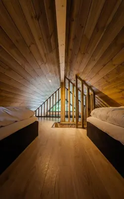 two beds in a room with wooden floors and windows at Flåm Minisuite in Aurland
