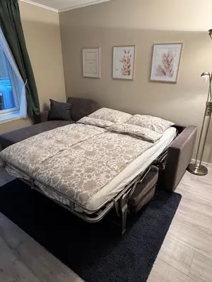 a large bed in a room with a bed frame at Stor attraktiv studioleilighet i sentrum in Trondheim