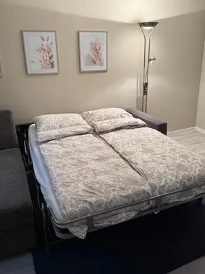 a bed in a bedroom with a lamp and pictures on the wall at Stor attraktiv studioleilighet i sentrum in Trondheim