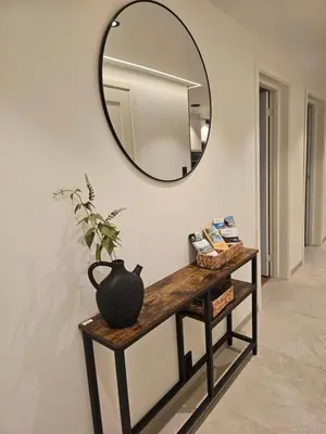a mirror and a table with a vase on it at Over the Fjord in Leikanger