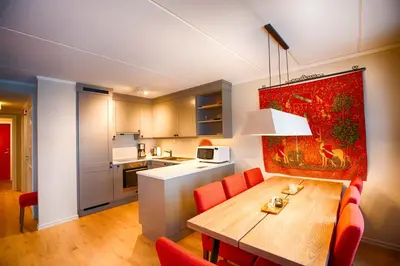 a kitchen and dining room with a wooden table and red chairs at Handicap-friendly apartment with 3 bedrooms in Beitostøl