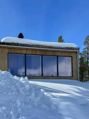 a house covered in snow with a lot of windows at Cozy Cabin At The Gateway To Jotunheimen in Vaga