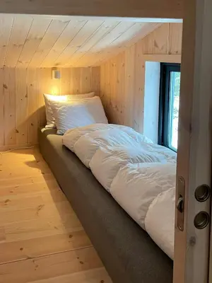 a large bed in a room with wooden walls at Cozy Cabin At The Gateway To Jotunheimen in Vaga