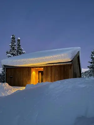 a building covered in snow next to a pile of snow at Cozy Cabin At The Gateway To Jotunheimen in Vaga