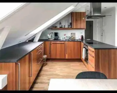 a large kitchen with wooden cabinets and a staircase at Penthouse Ålesund city center in Ålesund