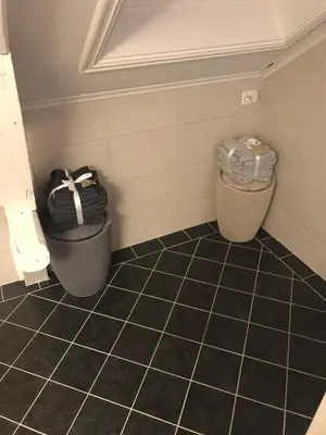 a bathroom with two trash cans and a tiled floor at Penthouse Ålesund city center in Ålesund