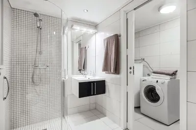 a bathroom with a shower and a washing machine at Romslig leilighet med to soverom pluss hems med dobbeltseng in Bergen