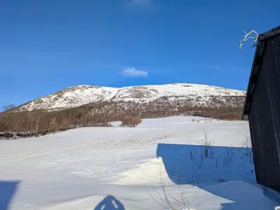 a snowy field with a mountain in the background at Three bedroom home with an amazing mountain view! in Oppdal