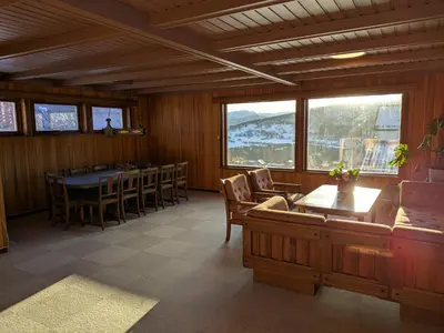 a dining room with a table and chairs and windows at Three bedroom home with an amazing mountain view! in Oppdal