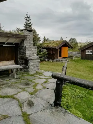 a bench and a building with a grass roof at Historic Log Cabin By Rondane National Park in Lårgard