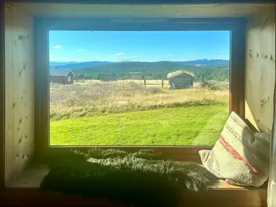 a window with a view of a field and a barn at Historic Log Cabin With Views Of Rondane in Ringebu