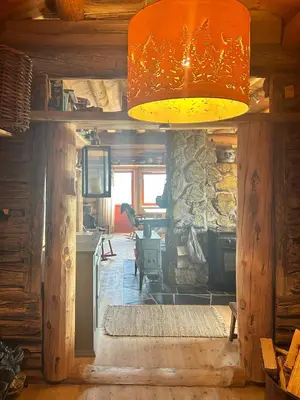 a living room with a stone fireplace and a lamp at Historic Log Cabin With Views Of Rondane in Ringebu
