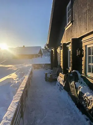 a house with snow on the ground next to a building at Family Cabin At Blefjell in Lampeland