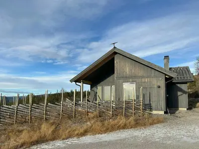a small wooden building next to a fence at Modern Mountain Cabin Near Norefjell in Eggedal