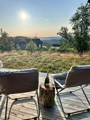 two chairs and a bottle on a stump on a deck at Modern Cabin With Panoramic Views At Nesfjellet in Nesbyen