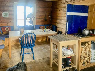 a kitchen with a wooden table and a blue chair at Traditional Mountain Cabin Near Hallingskarvet in Torpo
