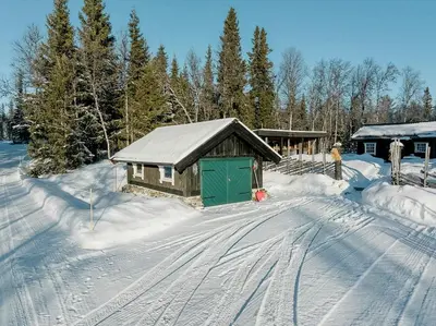 a snow covered cabin with a green door in the snow at Family Cabin With Shelter By Lake Gautetjern in Gol