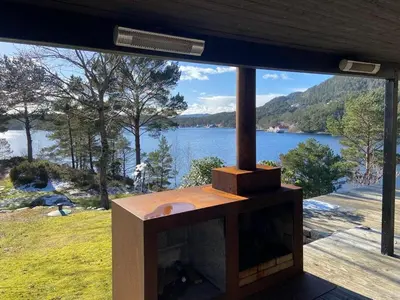 a wood stove with a view of a lake at Sea Cabin With Views On Kallevikevegen in Mosterhamn