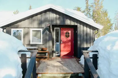 a red door on a wooden house with snow at Charming Cabin In Vikerfjell in Hønefoss