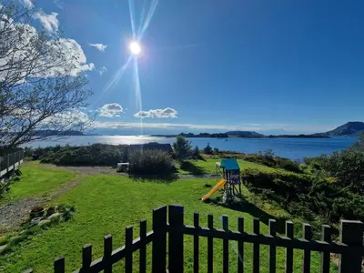 a fence in a field with a view of the water at Færøya 49 in Nekkøyane