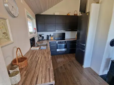 a kitchen with a black refrigerator and wooden floors at Færøya 49 in Nekkøyane
