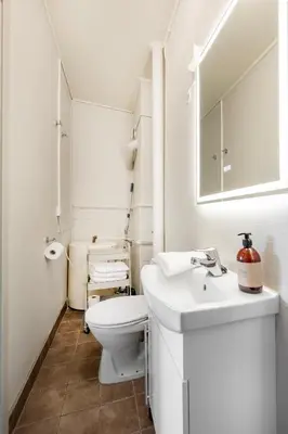 a white bathroom with a toilet and a sink at Jugend 1904 in Ålesund