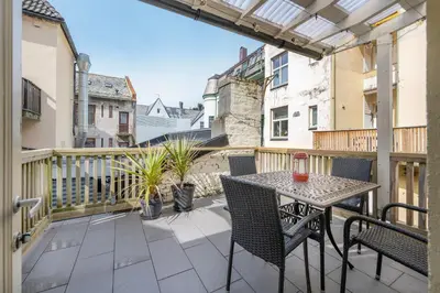 a patio with a table and chairs on a balcony at Jugend 1904 in Ålesund