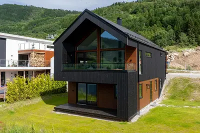a black house on the side of a mountain at Top-Floor Lakefront Apartment near Ski Resort in Hafslo