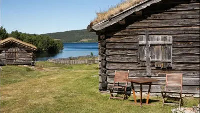 two chairs and a table in front of a log cabin at Ski in & out hytte på Lemonsjøen i Jotunheimen in Randsverk