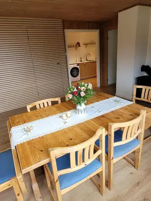 a wooden table with chairs and a vase of flowers on it at Adventure house Katrine in Mosvik
