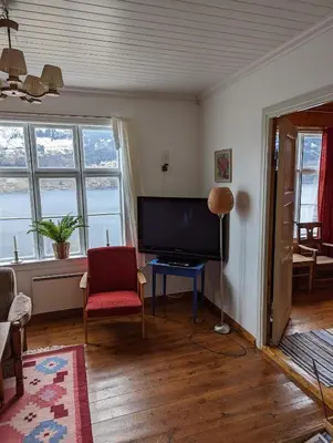 a living room with a television and a red chair at The queen path right from the house in Tveit
