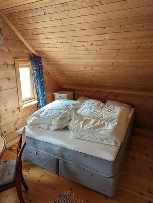 a bed in a log cabin with a window at The queen path right from the house in Tveit