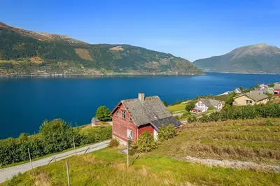 a house on a hill next to a body of water at The queen path right from the house in Tveit