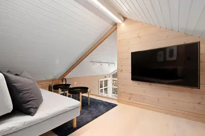 a living room with a couch and a tv on a wall at Idyllic Apartment at Strandafjellet in Stranda