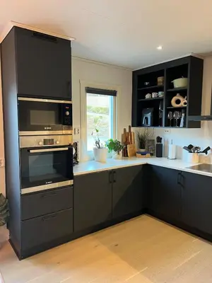 a kitchen with black cabinets and a microwave at Bergen - Home, Close to Airport and the city in Bergen