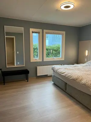 a bedroom with a bed and two windows at Bergen - Home, Close to Airport and the city in Bergen