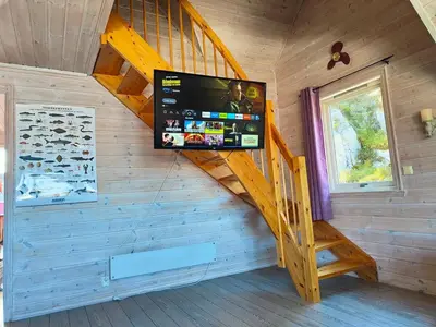 a staircase in a log cabin with a tv on the wall at cozy house with boat dock, sauna - FJORDTID in Rubbestadneset